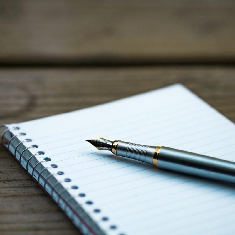 image depicts a blank notebook and fountain pen which suggests a blank page ready for the story