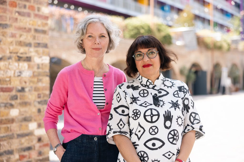 Two women stand outside one has a white bob the other has a brown bob