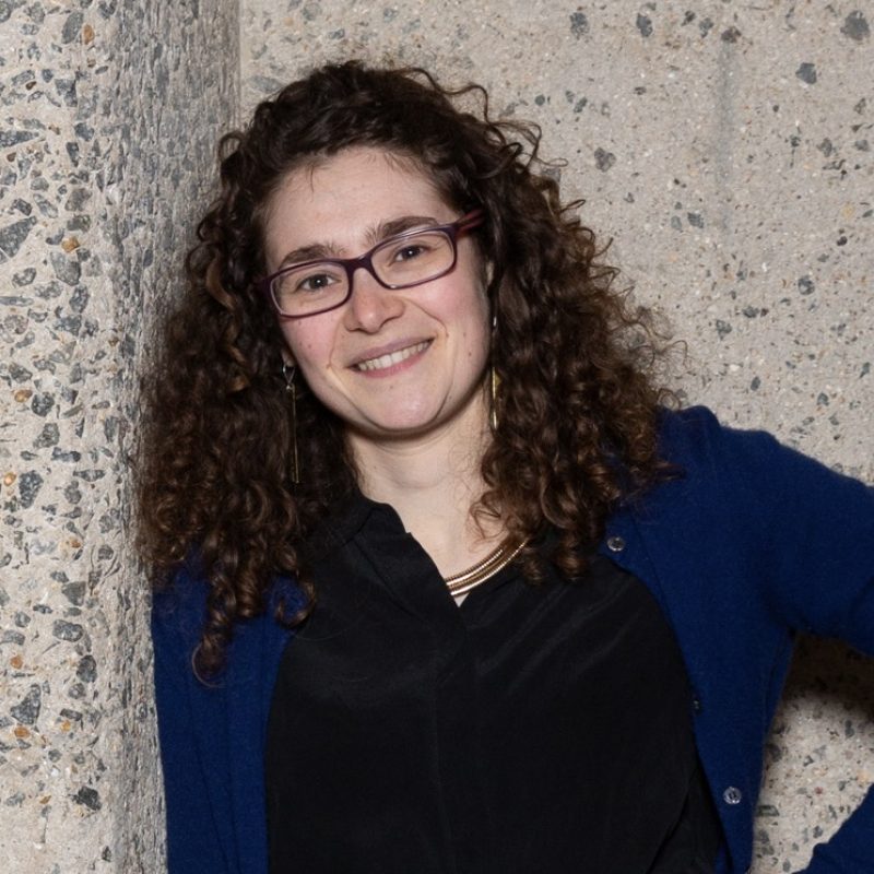 Image shows a woman smiling with curly long hair